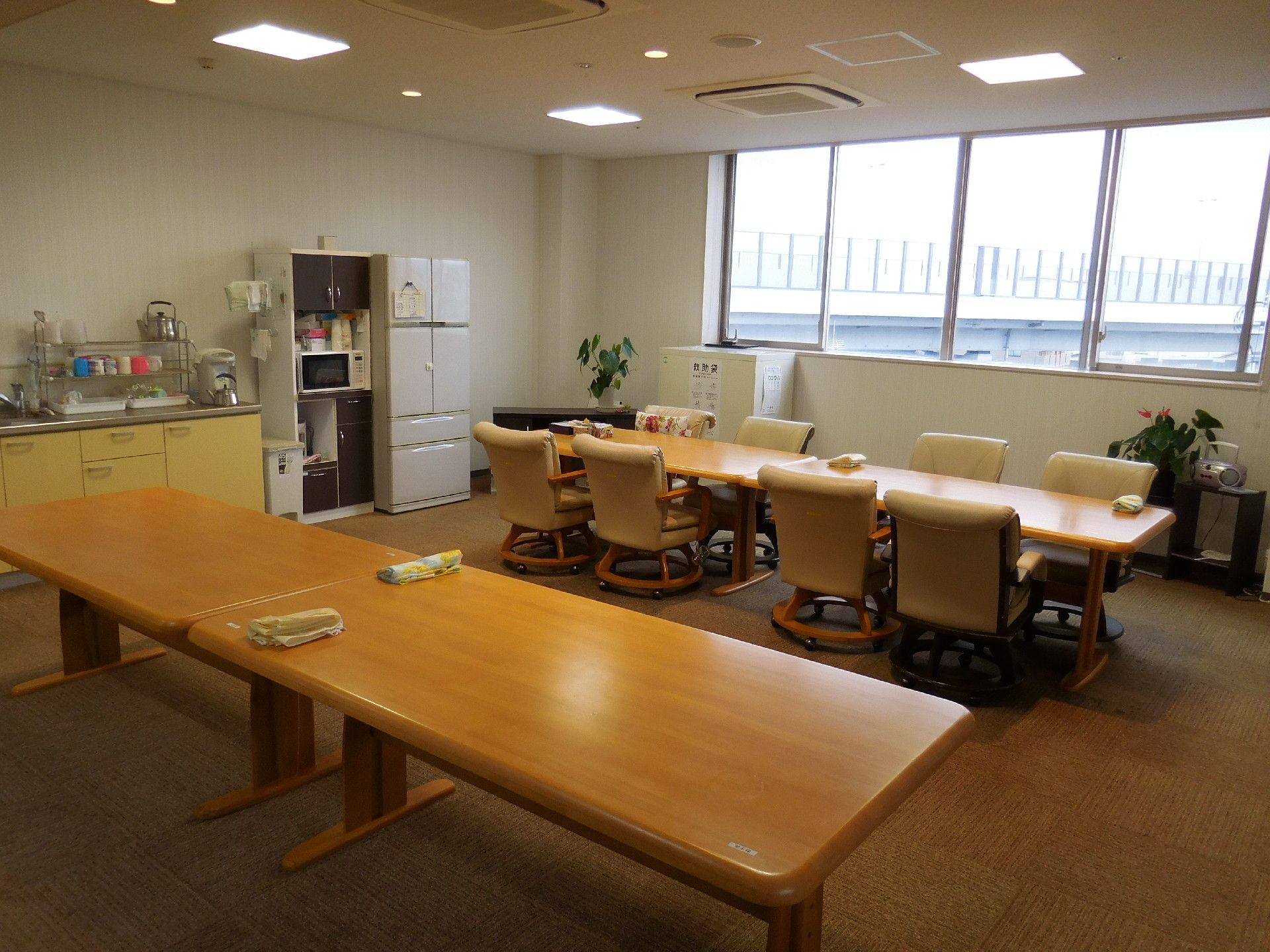 施設のリビングは広いホールに長テーブルと椅子が置かれている。壁際には冷蔵庫や電子レンジ、簡易的なキッチン設備もある。