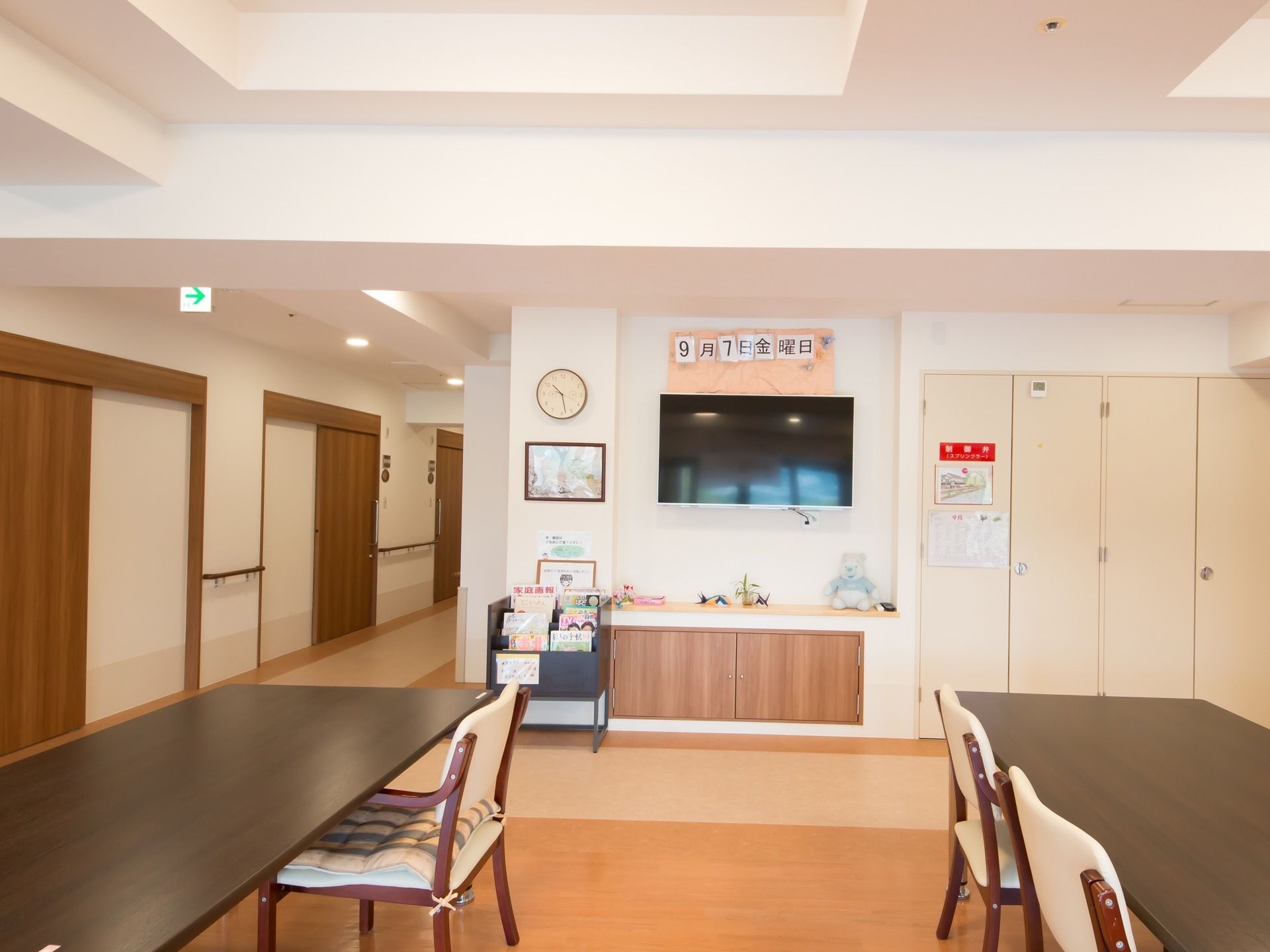 居室のすぐ傍にある広々としたフロア。壁に掛けられた大型テレビの下には棚があり、可愛らしい小物が飾られている。