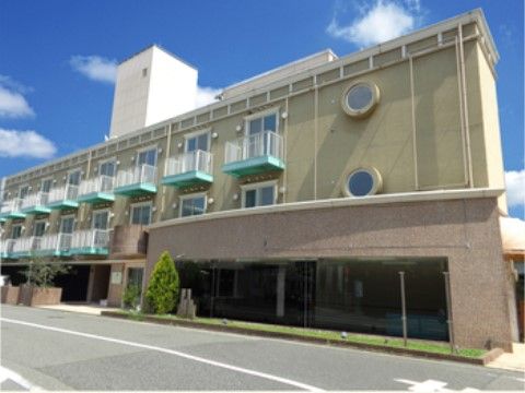 各居室にあるバルコニーの緑色が印象的な、３階建ての施設外観