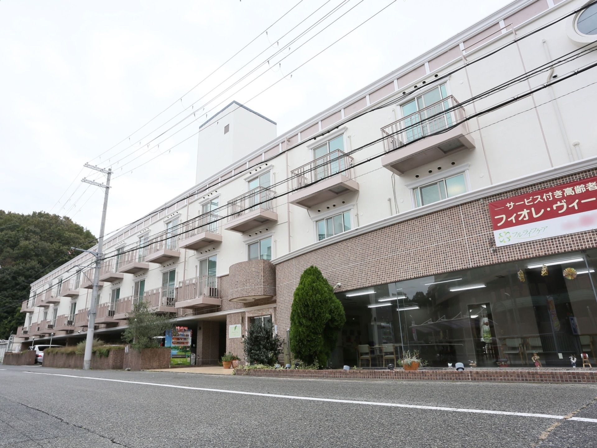 3階建ての建物は、施設の前を通る道路に面して建っている。道路からは入居者様の居室に備わるベランダを見ることができる。