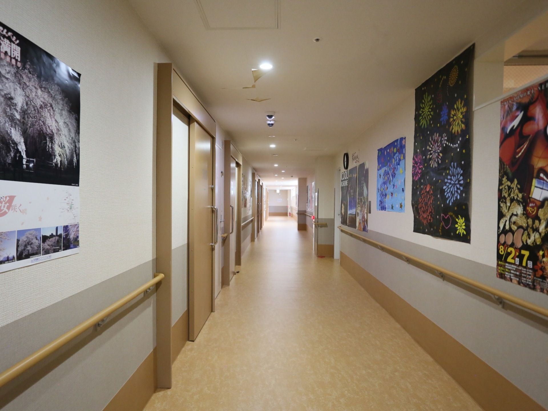 居室のドアの前の通路には手すりが備わっており、壁には入居者様がレクリエーションで製作した作品やイベントの案内が掲示されている。