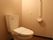 トイレの個室内は、茶色系の木目を基調とした空間である。壁には手すりと緊急時呼び出しブザーが取りつけられている。