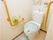 トイレには山吹色の手すりが、くの字に渡してある。便座を利用する時に掴まることができる位置には、床と平行な手すりがある。