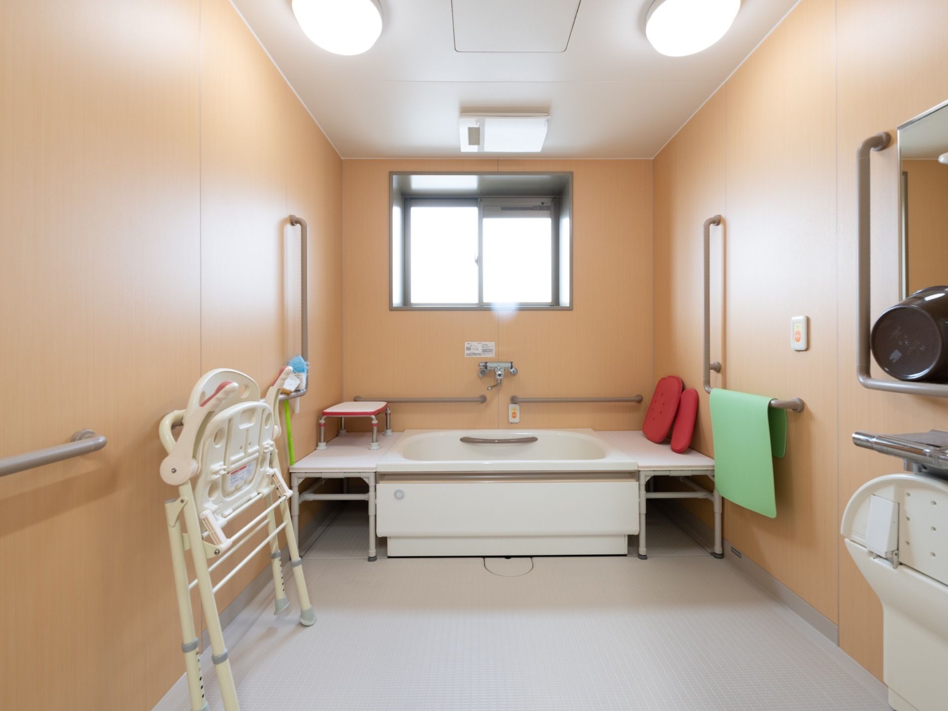 広い洗い場があり、シャワー椅子が畳んで置かれている。壁や浴槽の近くには、手すりが取りつけられている。