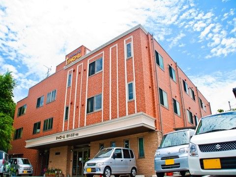 オレンジ色の外壁が明るい印象の、３階建ての施設外観