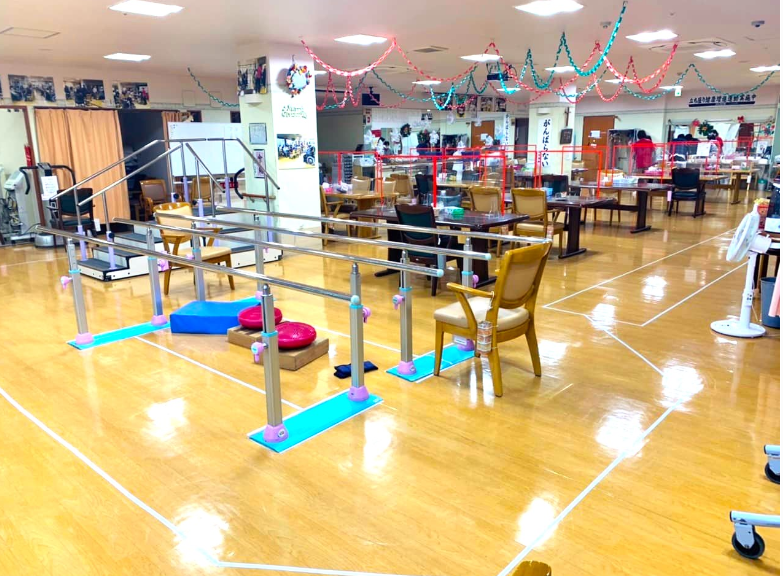 多くのテーブルと椅子が置かれ、キッチンカウンターが見える食堂