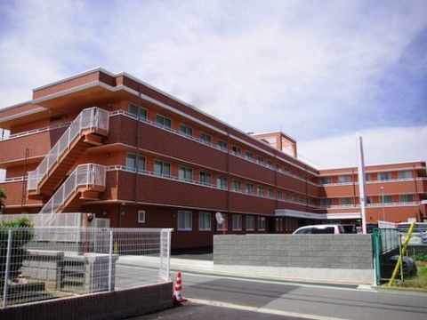 敷地境界にブロック塀が設置されている、３階建ての施設全景外観