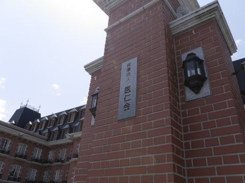 縦長の施設看板が取り付けられている、レンガ積みの重厚な門柱