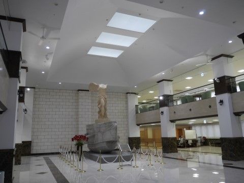 天井の照明で照らされ、ロープがついた柵で囲まれている金色の像