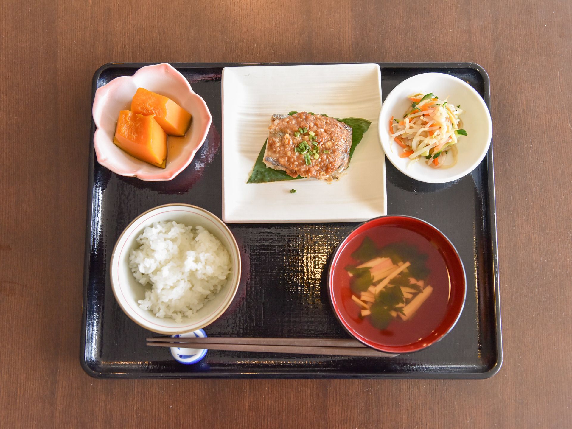 黒いトレーの上にご飯と汁物、メインおかずと2つの小鉢。高齢者に考慮されたバランスのとれたメニューになっている。