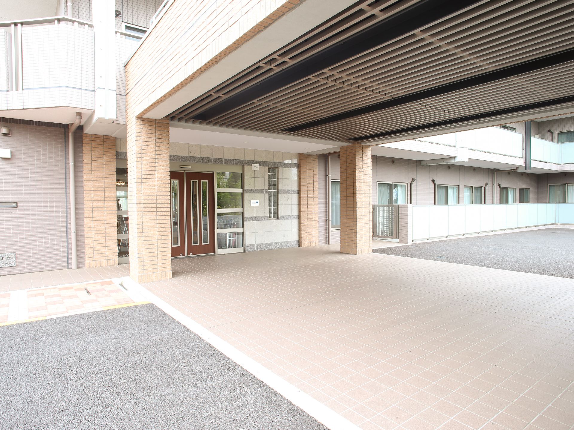 ドアは茶色い自動ドア。エントランスには大きな屋根が付いているので雨や雪の日でも濡れずに移動ができる。