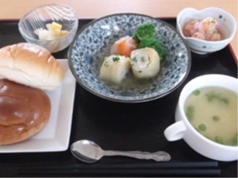 主菜のお皿の周りにコッペパンやスープが置かれているお食事のプレート