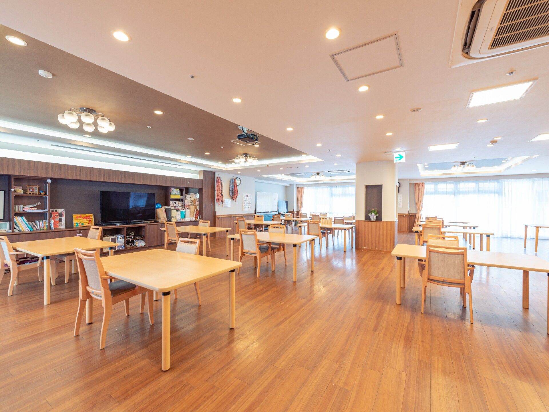 暖色系の照明で照らされたフロアに、間隔を空けてテーブルが置かれている食堂