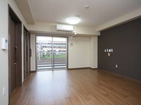 居室はガラス引き戸でベランダにつながっており、室内の床はフローリングである。エアコンが設置され、天井には照明が整っている。