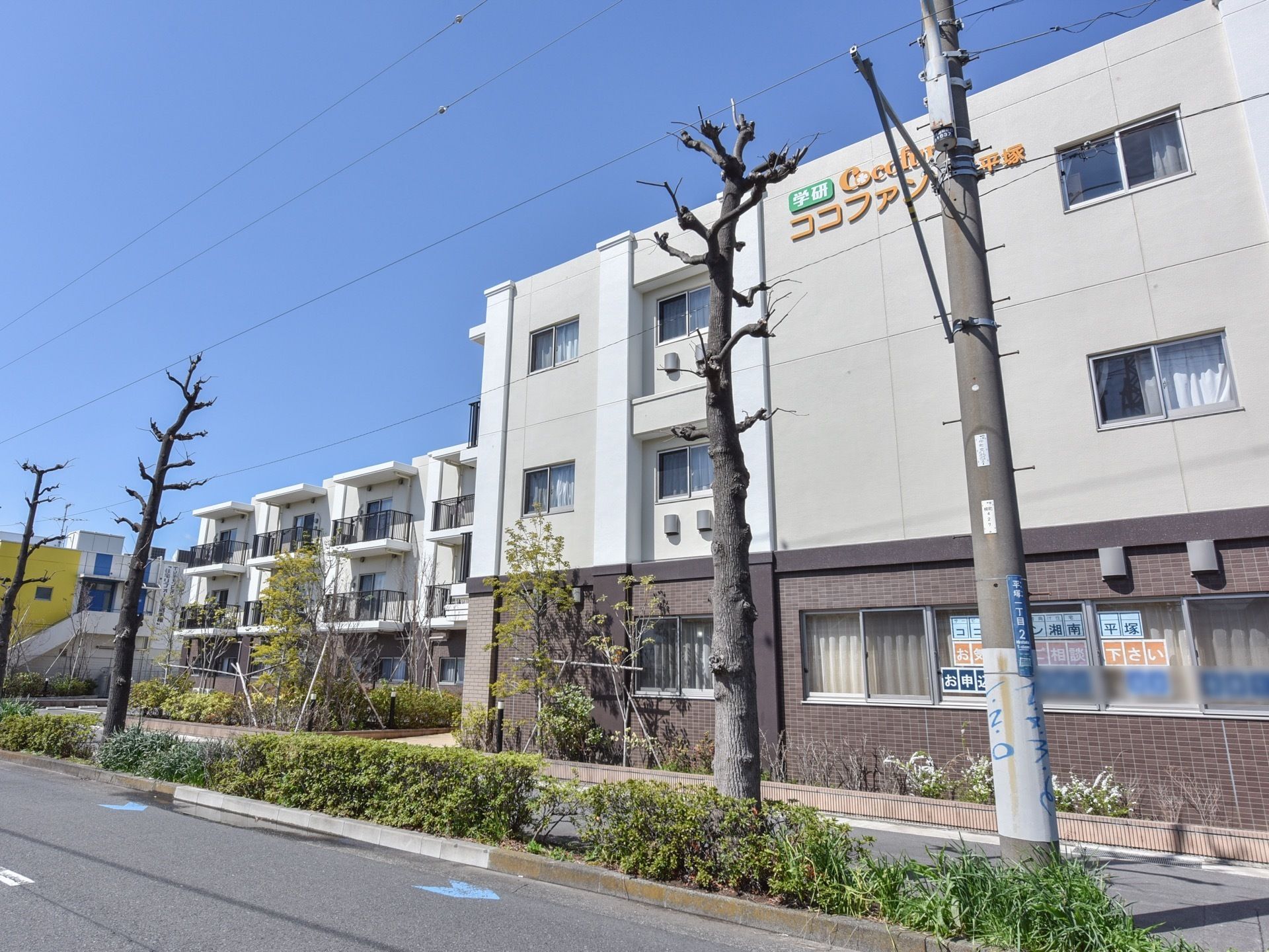 3階建てのマンションのような見た目の建物。道路沿いに面しているが植物も多く、穏やかな印象になっている。