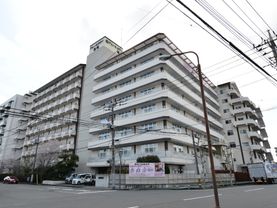施設の目の前は広い道路となっており、正面に施設名が書かれている看板が掲げられている他、車も数台停まっている。