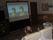 入居者様がゆったりとしたソファーに座り、映画鑑賞をしている。プロジェクターと大画面スクリーンが設置されている。