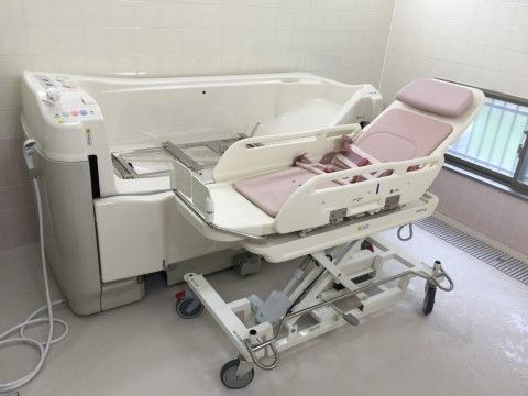 入居者様が横になった体勢のまま入浴することができる機械浴槽が置かれている。浴槽などは白を基調としており、清潔感が感じられる。