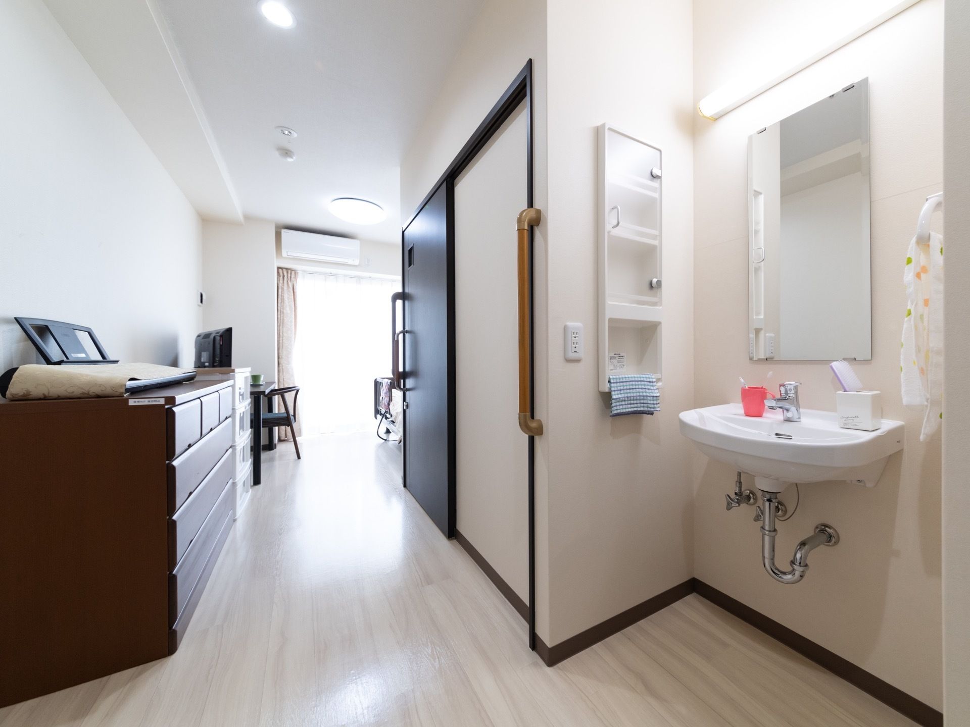 居室はフローリングとなっており、壁が白く清潔感がある。洗面台があり、レバー式の水栓で簡単に操作することができる。