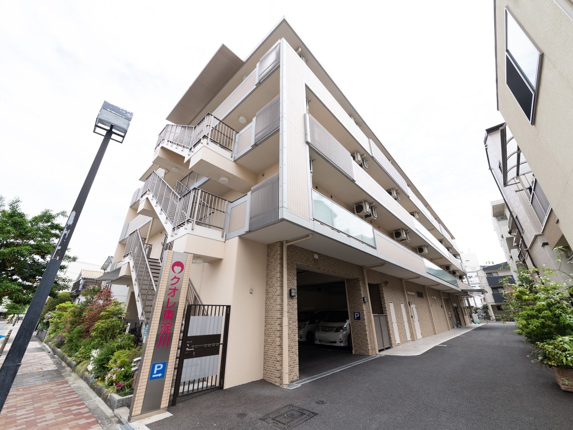 薄いベージュ色の外壁の落ち着いた雰囲気の建物である。1階部分には駐車場を備えており、車での来訪も便利である。