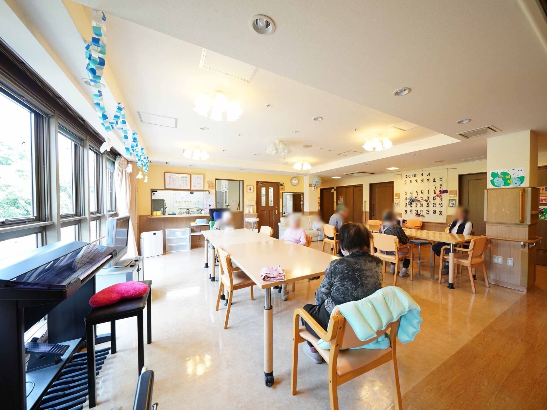 壁と床とテーブルに木材を使用して統一感がある。天井が窓に向かって高くなっており、窓側にテレビやピアノが設置してある。