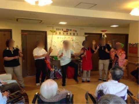 車いすに座った入居者様たちの前で皿回しの芸をしている方々