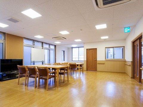 窓近くの壁際に大画面テレビ、その右側にホワイトボードが置かれている共有スペース