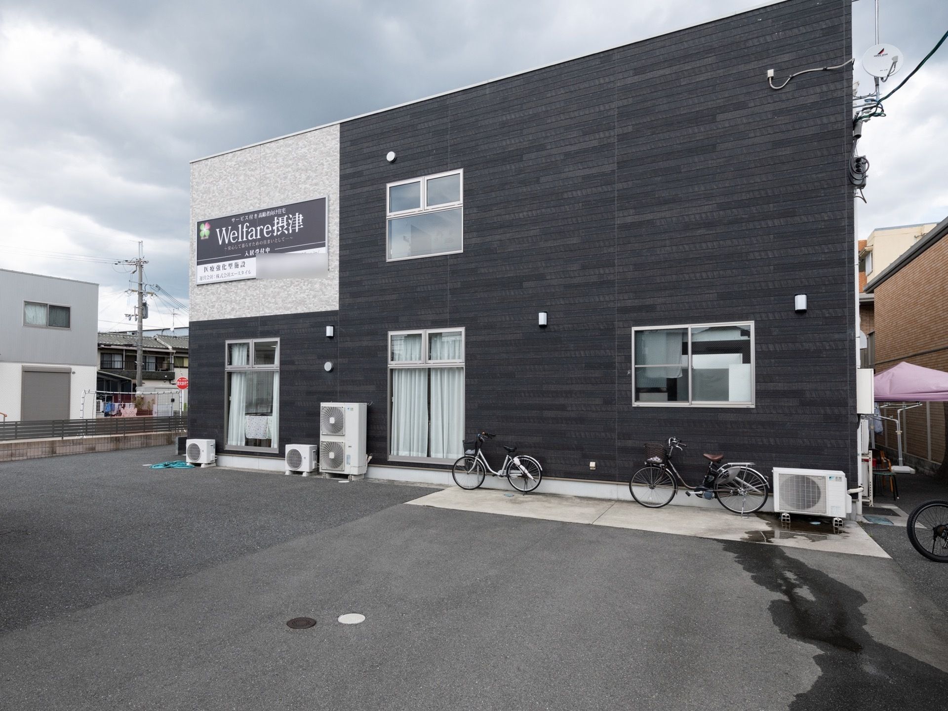黒と灰色の配色の外壁で、落ち着いた雰囲気のある建物である。建物周囲は駐車ができるように整地されている。