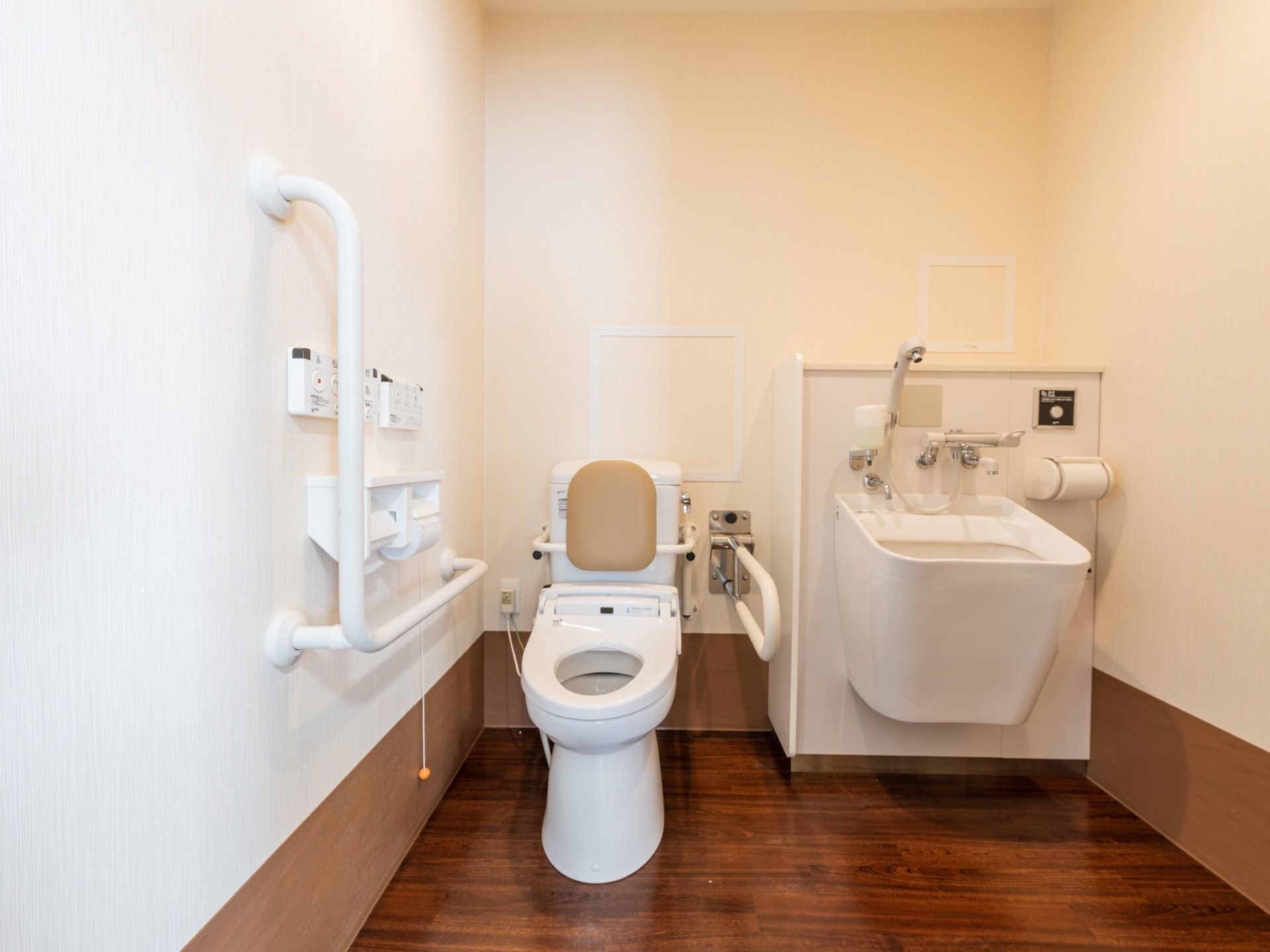 トイレの便座には後ろに背もたれがついており、左右に手すりが設置されている。隣にはオストメイト対応の洗浄台がある。
