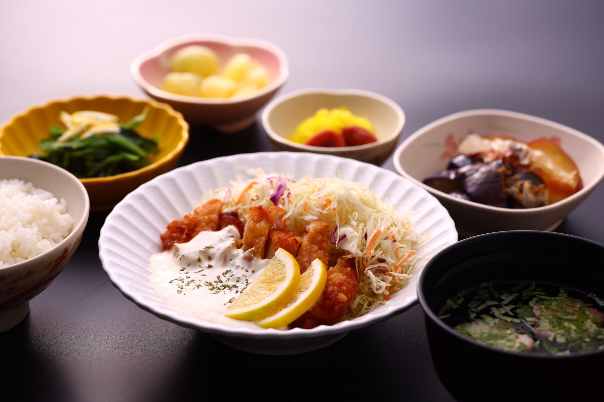 テーブルの上に料理が6品載っている。ご飯、みそ汁、和え物、果物、おでん、野菜炒めが載っている