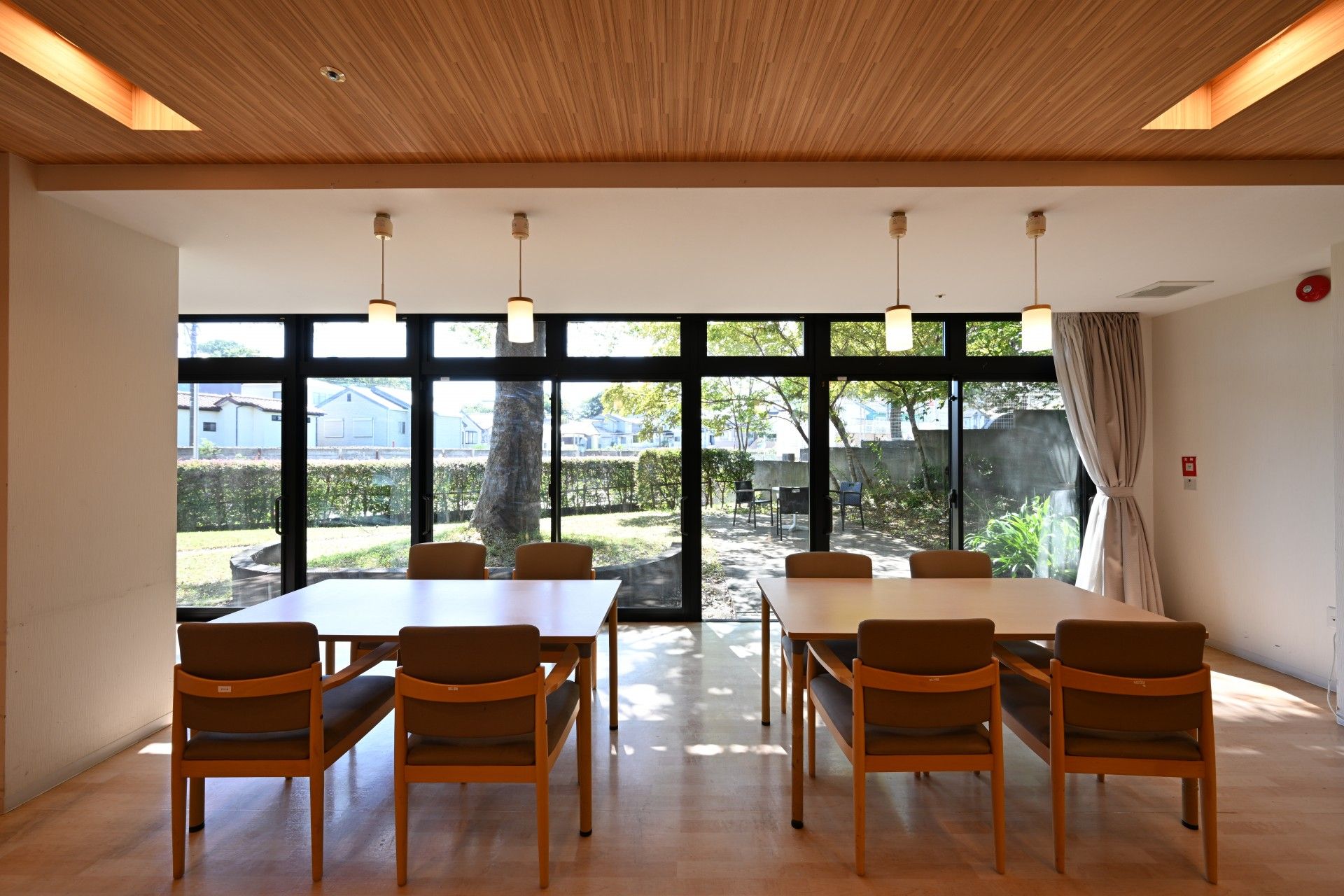 窓から光が差し込み、天井からは照明器具がぶら下がっている食堂