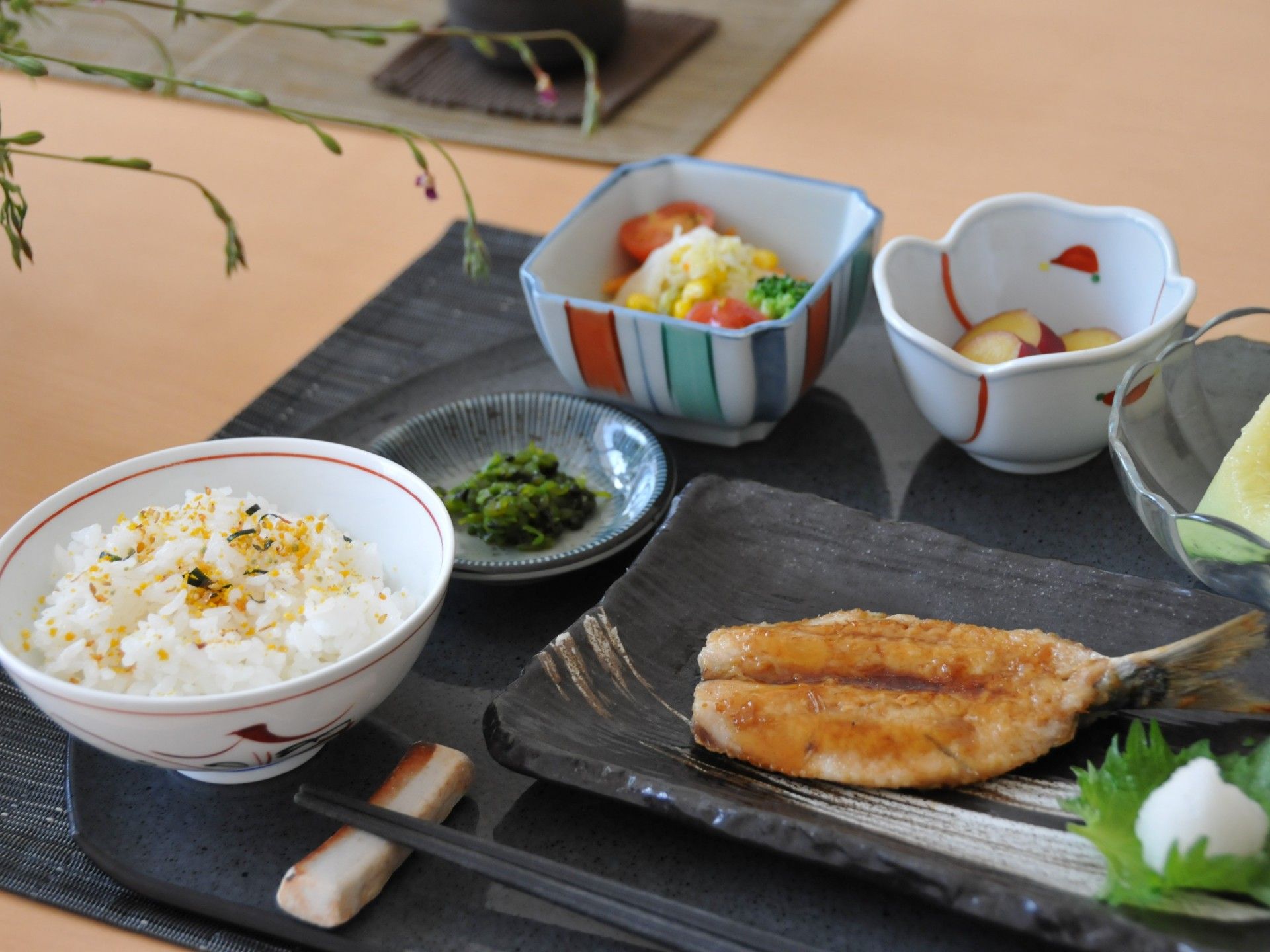 黒色のプレートに載っている、季節のフルーツもついたお食事