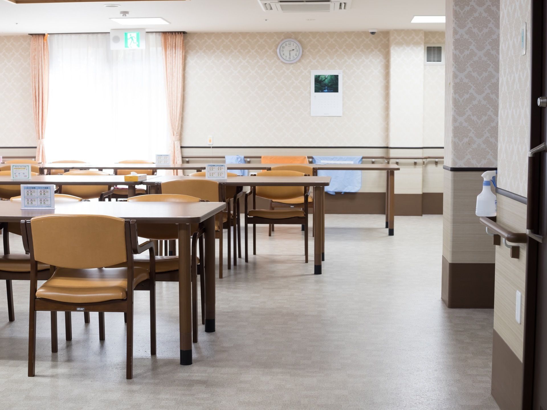 食堂はゆったり広々としていて木の温かみを感じるテーブルと椅子が複数設置されている。大きな窓にはレースのカーテンがかかっている。