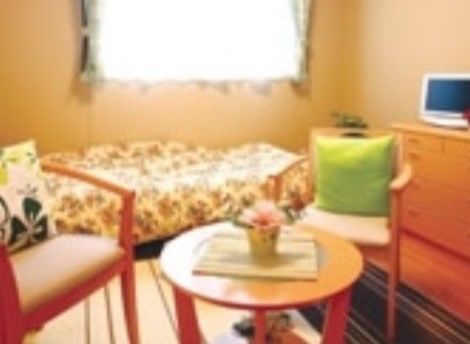 クッション付きの椅子と机、ベッドが置かれた一人暮らし向きの部屋