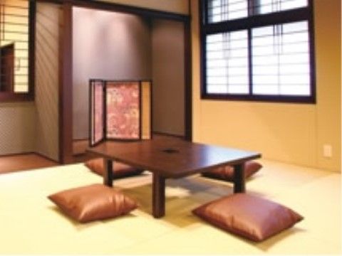 ざぶとんが置かれたテーブルと桃色の屏風がある小さな和室