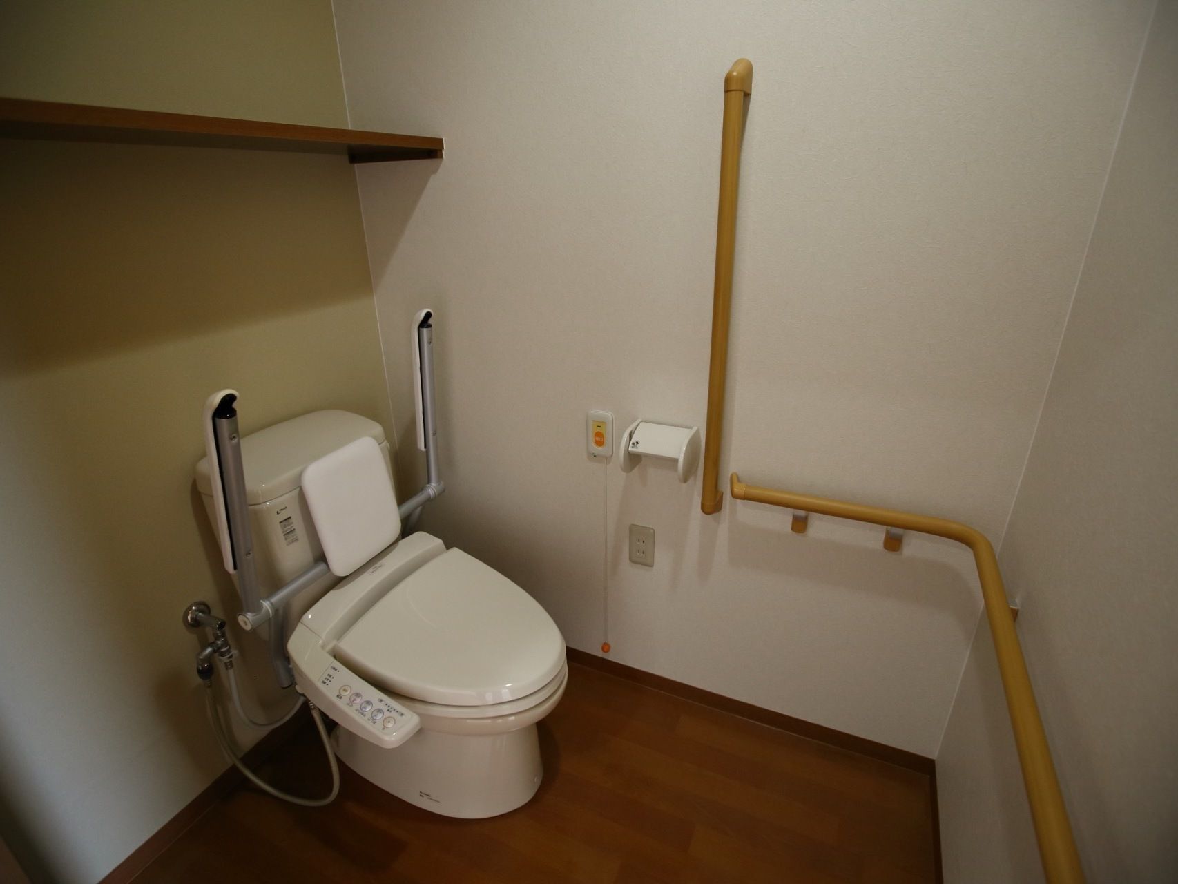 トイレには、可動式手すりと背もたれパッドが取り付けられた温水洗浄便座器が完備されている。壁伝いに手すりが設置されている。