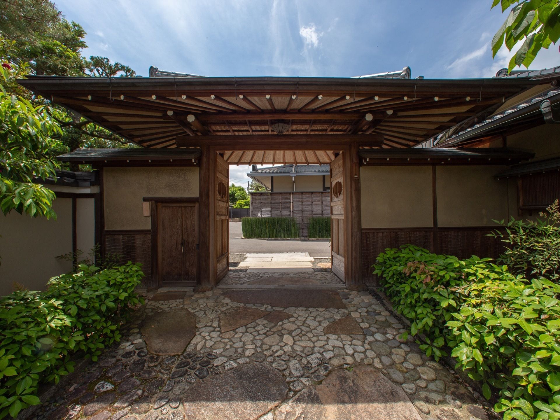 日本建築の大きな屋根が付いた、木製の観音開きの門と石畳