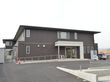 2階建てのシンプルな雰囲気の建物。周りは自然に囲まれた好立地。建物周辺には自動販売機と駐車場がある。