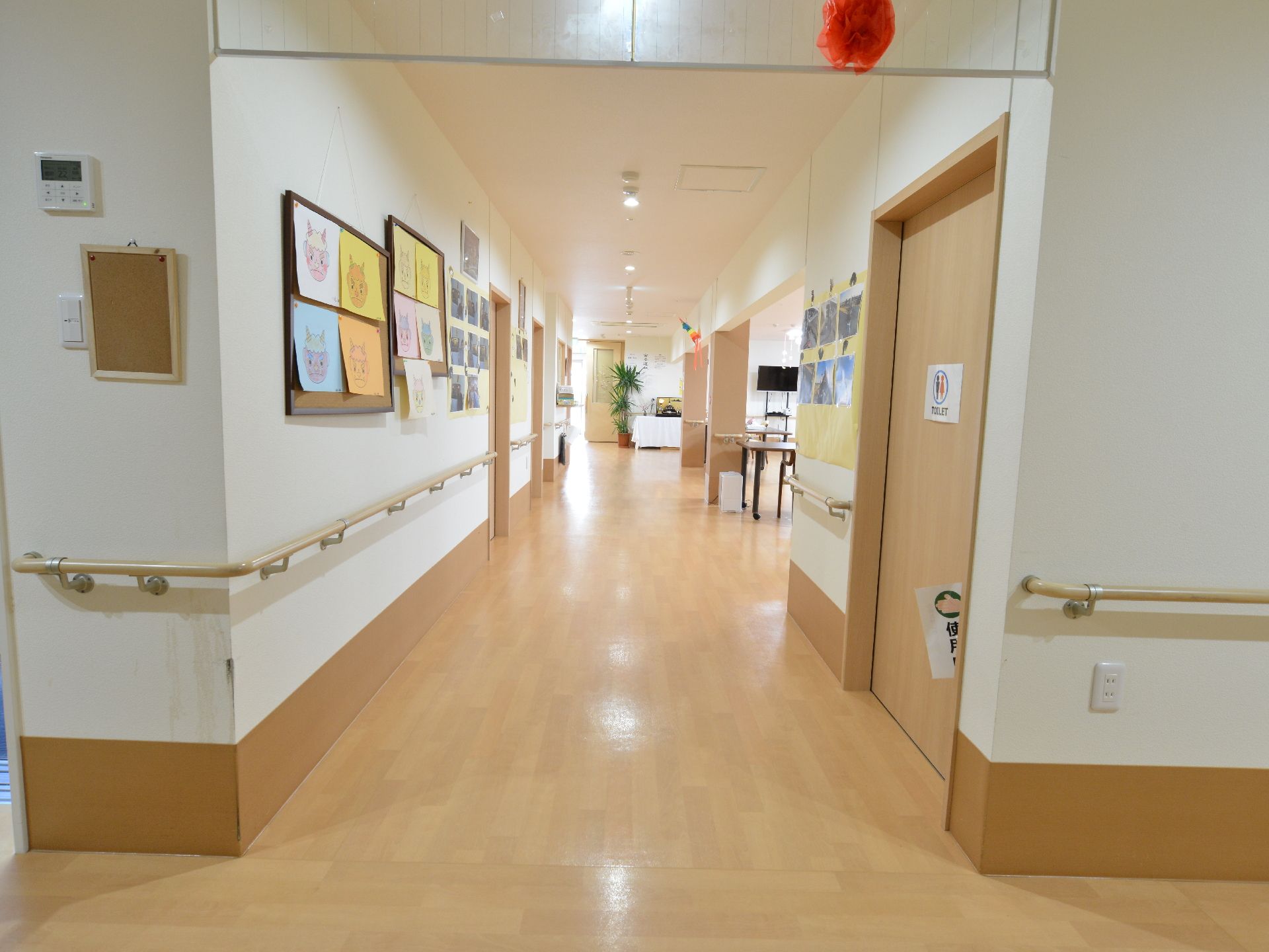 広々とした明るい廊下の壁には掲示板があり連絡事項が掲示されている。また、手すりの完備で安全に歩行ができる。