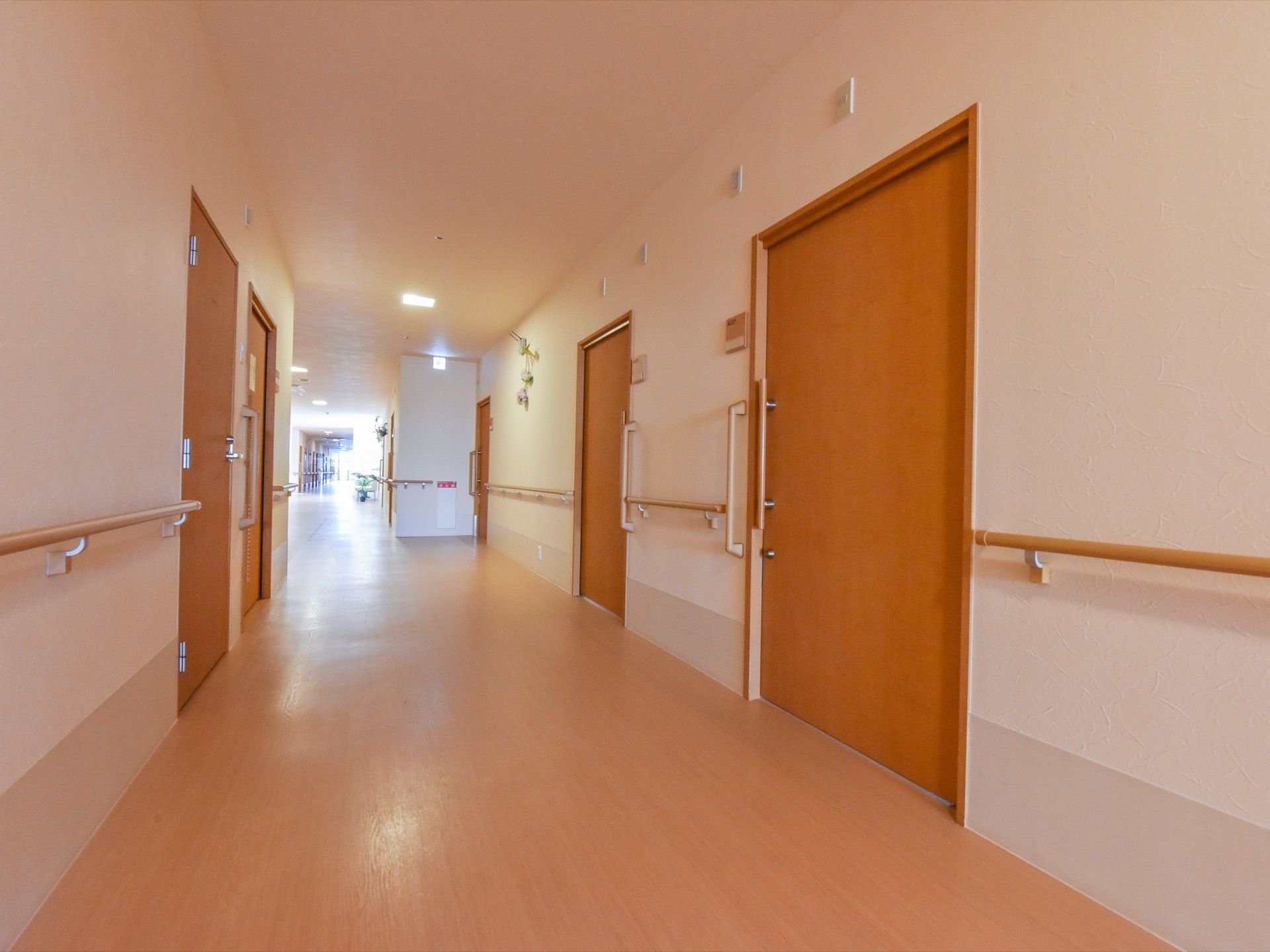 通路の両側に並んでいる居室の扉はスライド式である。扉のそばには、垂直方向にも手すりが取り付けられている。