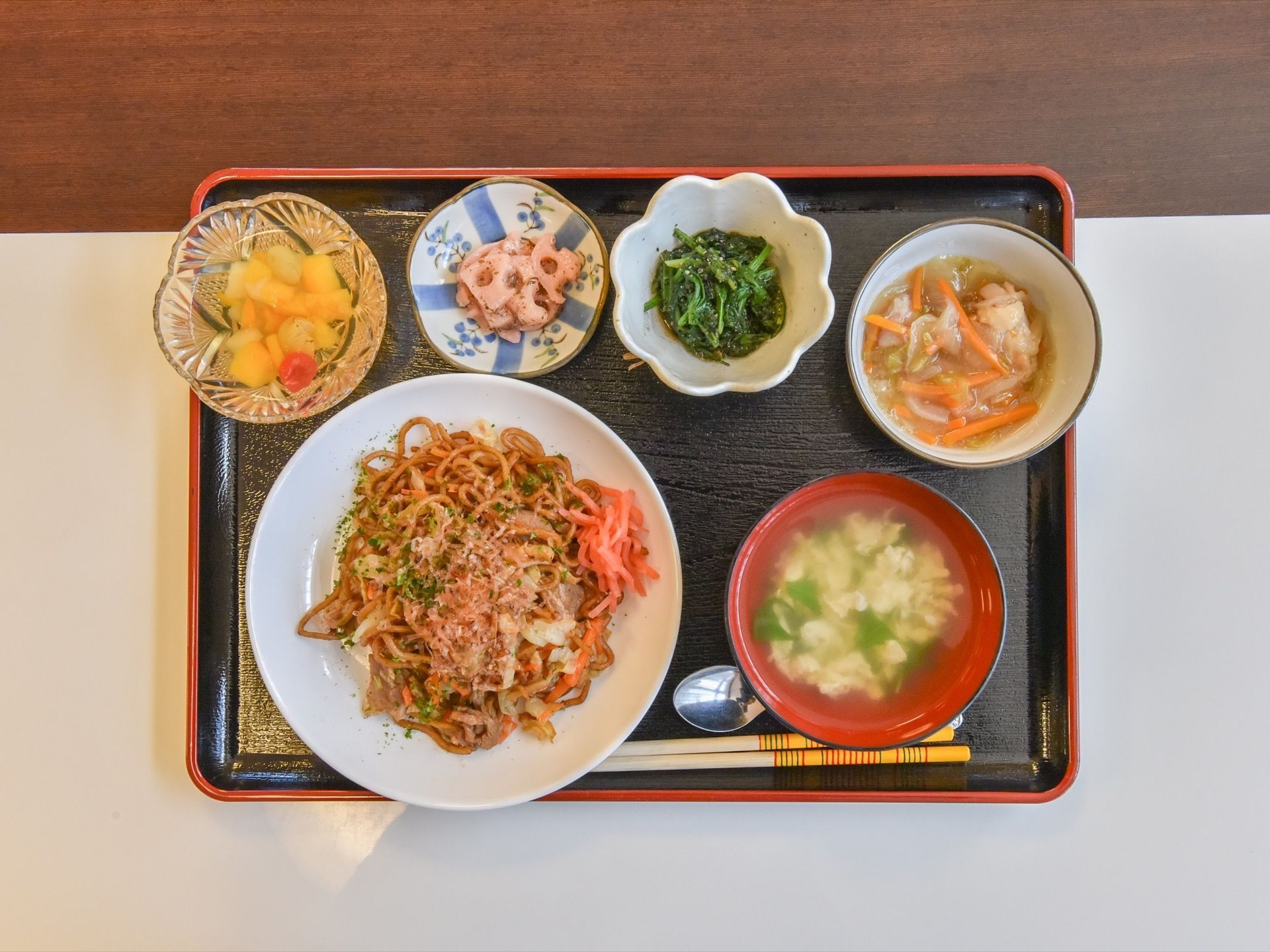 主食は焼きそばである。副菜が3品と汁物、デザートが添えられている。食事は、緑・赤・黄色と彩りが考えられて作られている。