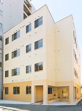 ベージュの外壁が特徴的な、V字型の4階建ての施設外観
