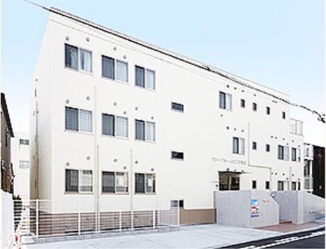 白い外壁が目立つ、駐車スペース付きのマンション型施設外観