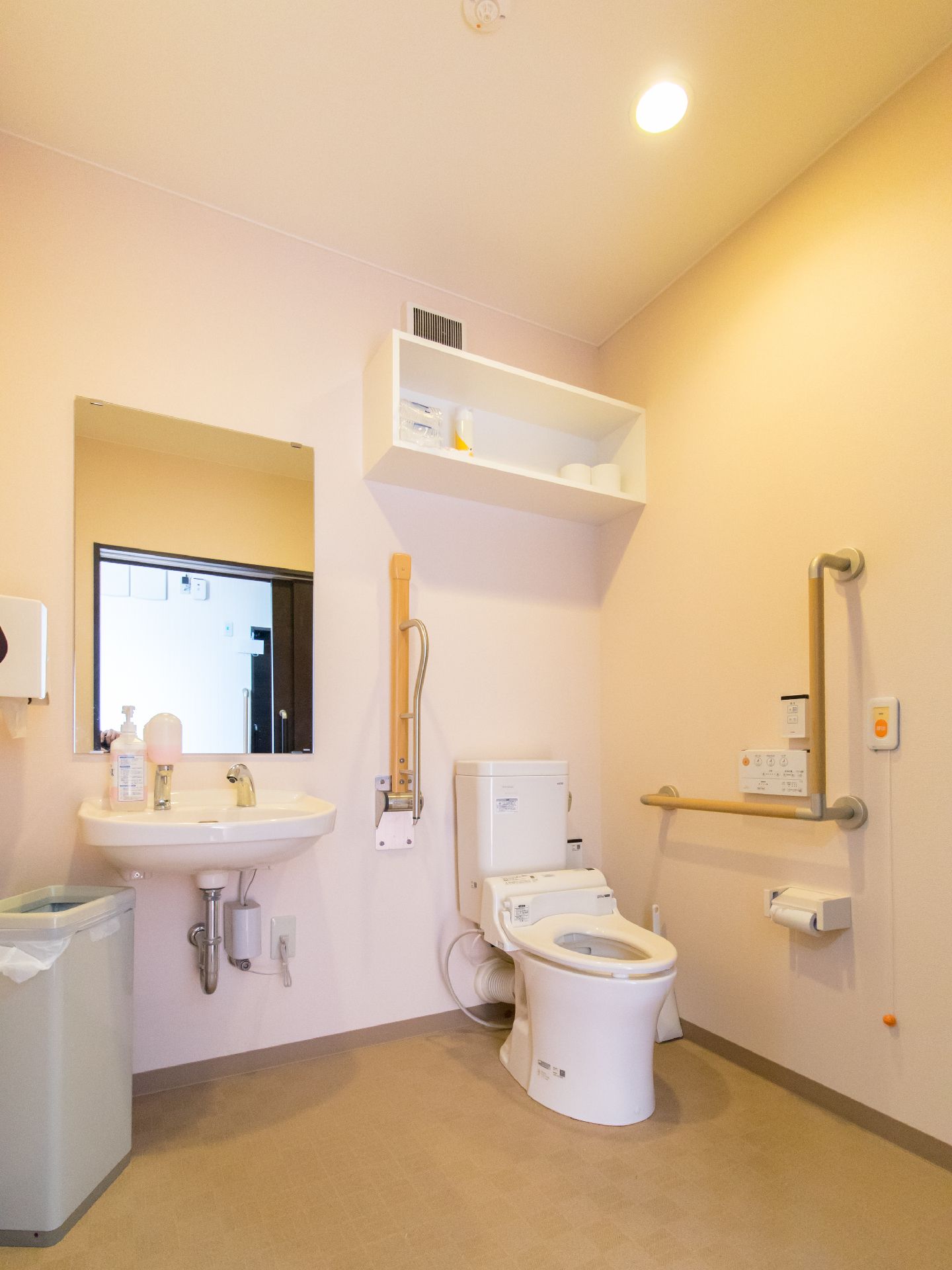 トイレは広く、温水洗浄便座になっている。ボタンが壁に設置されているので押しやすい。上部に棚があり、独立した洗面台もあるので便利である。