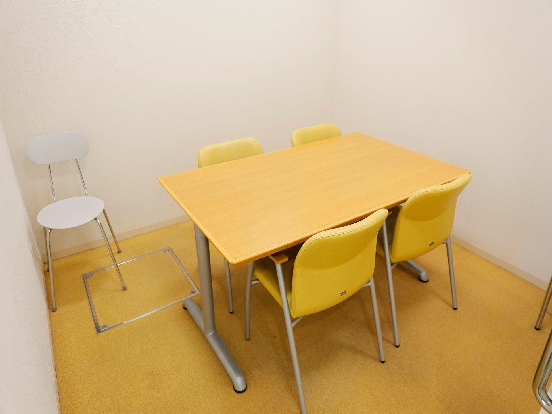 木製のテーブルに鮮やかな黄色の椅子が設置されている相談室がある。スタッフ、入居者様とご家族様がお掛けできるスペースがある。