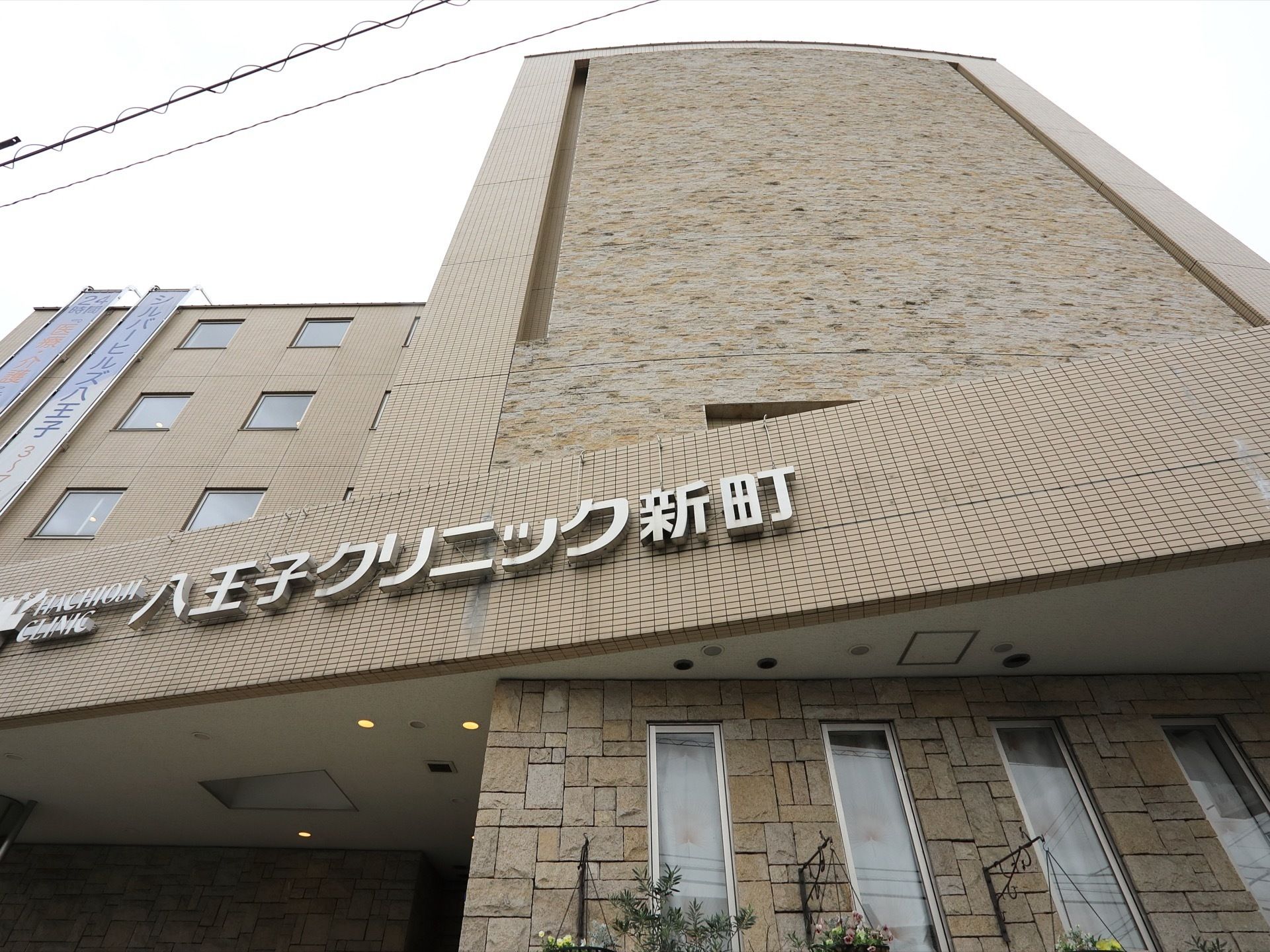 高級ホテルのような重厚さがある施設の外観。正面部分の外壁にはブラン系のレンガになっている。建物の周りには花が植えられている。