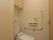間口が広くとってある広々としたトイレ。トイレ内には緊急通報装置が設置されている。天井部分に収納スペースが設けられている。