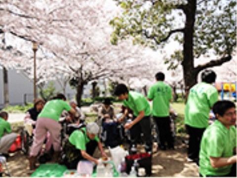 桜の木の下で花見の準備をする入居者様とスタッフたち