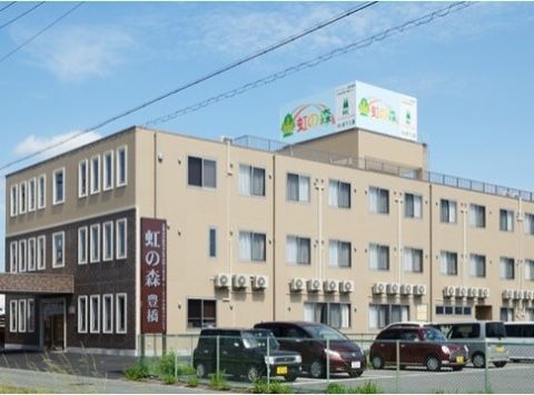高齢者施設の外観。屋上の上に施設名の書かれた大きな看板が付いている。