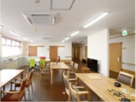 窓からの光と天井の照明が廊下まで届く、明るく開放的なスペースである。木製テーブルを並べテレビも備え、天井には監視カメラが付いている。
